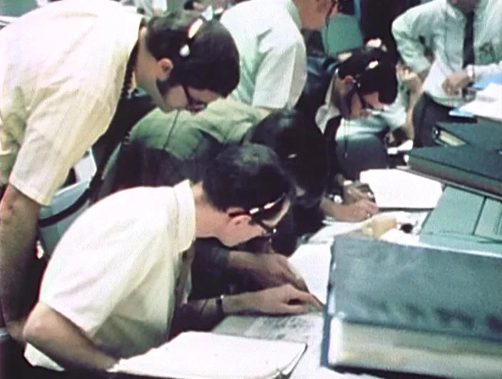 NASA Flight Controllers working the Apollo 13 problem at their stations.